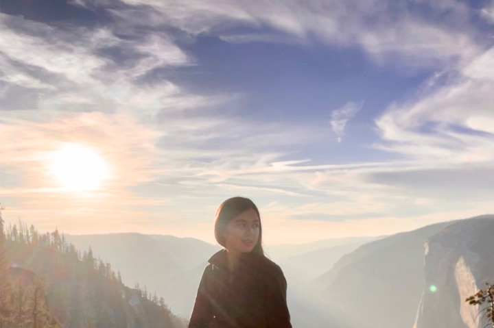 Kaitlyn sitting on granite at sunset above a misty blue mountain valley